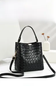 Detail of black woven leather bucket bag with gold hardware and adjustable strap