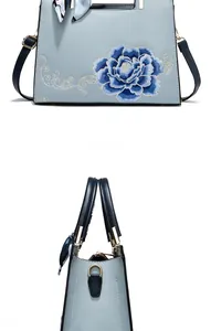 Détail du sac cabas bleu clair avec broderie florale et anse ornée d'un foulard