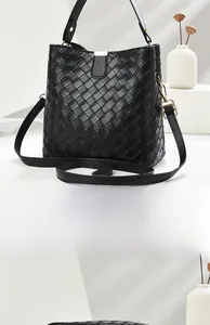 Detail view of black woven bucket bag showing intricate checkerboard texture and gold hardware