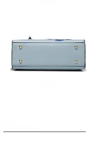 Détail du fond d'un sac à main en cuir bleu clair avec quatre pieds de protection dorés