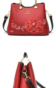 Makro-Detail der roten Blumenstickerei und des goldenen Ringgriffs der Luxushandtasche