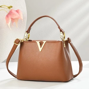 Detail einer karamellfarbenen Lederhandtasche mit goldenem V-Logo und Beschlägen