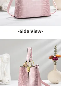 Side view of pink crocodile embossed handbag with glossy finish and gold metal ring hardware