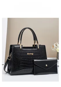 Detail of black crocodile pattern tote bag set with golden emblem on white pedestal