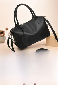 Close-up of black leather Boston handbag with gold hardware and removable shoulder strap