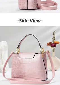 Side view of pink crocodile embossed leather bucket bag with gold hardware and strap