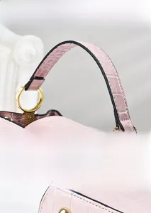 Detailed view of pink croc-embossed leather, golden round handle and fine stitching