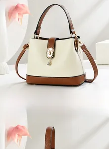 Dettagli della borsa a secchiello beige con finiture in pelle marrone e orso dorato
