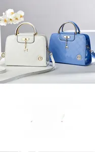 Detail of glossy quilted leather handbags in pearl white and sky blue with gold handles
