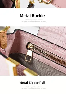 Detail of pink crocodile-textured leather handbag with golden hardware and zip closure