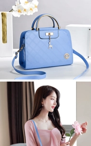 Detail of light blue glossy quilted handbag featuring golden elk pendant and top handle