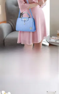 Detail of light blue quilted leather handbag with gold deer charm and top handle