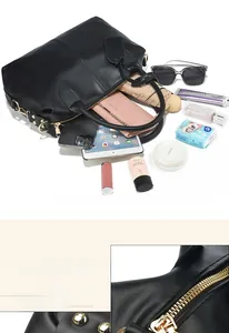 Detail view of large capacity black leather handbag with gold zippers and metal studs