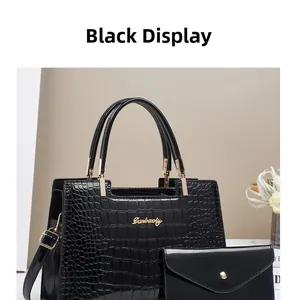 Detail view of black crocodile pattern patent leather handbag set with gold brand logo