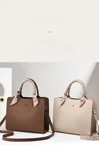 Détail de sacs cabas en cuir motif litchi avec poignées enroulées de foulard en soie rose