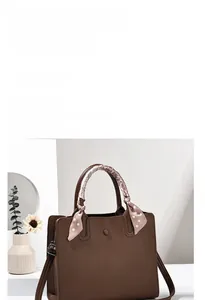 Détail du sac cabas en cuir grainé marron avec foulard en soie décoratif sur l'anse