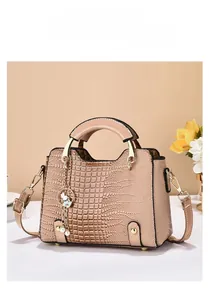 Close-up of nude crocodile embossed handbag featuring a cute pearl rabbit charm