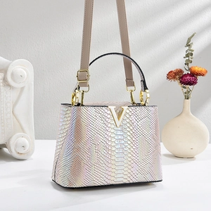 Elegant gradient crocodile pattern handbag with V-shaped gold logo on a stone pedestal