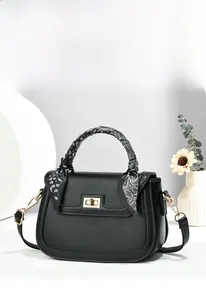 Detail of black leather crossbody bag with paisley silk scarf wrapped handle and gold buckle
