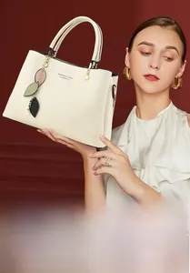 Detail of minimalist cream tote bag with leaf charms and Fashion & Classic lettering