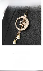 Detail of black lychee leather handbag featuring gold star and pearl charm hardware