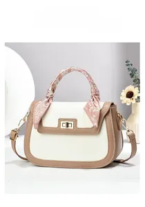 Detail of elegant two-tone handbag with silk scarf handle decoration and gold twist lock