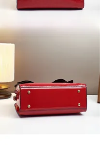 Detail der roten Handtasche mit Krokostruktur und vier goldenen Standfüßen am Boden