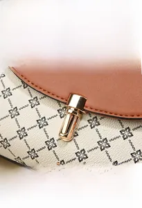 Close-up of golden metal clasp on vintage brown leather and monogram patterned handbag