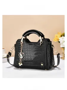 Detail of black crocodile pattern leather handbag with pearl bunny charm and metal handles