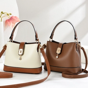 Trendige Eimertasche mit Farbkombination, Tragegriff und floralem Metallverschluss