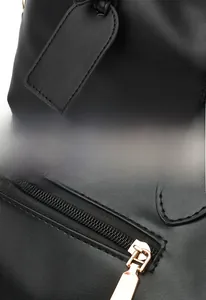 Detail of leather handbag showing quality stitching, metal zipper and stylish bag tag