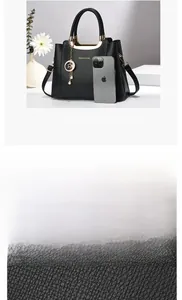 Close-up of black leather handbag featuring gold metal handles and lychee grain texture