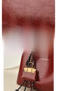 Détail macro de mini bijou de sac rouge foncé avec texture litchi et finitions dorées