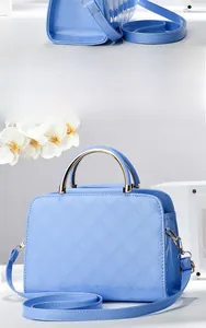 Detail of light blue quilted patent leather handbag with golden metal handles