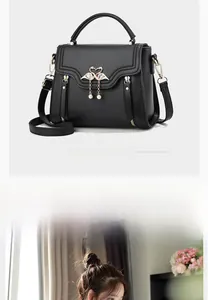 Detail of black textured leather bag with swan metal clasp and pearl tassel charm