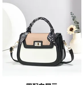 Close-up of tricolor handbag featuring silk scarf handle and elegant gold turn-lock