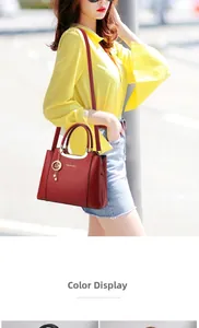 Detail of burgundy lychee leather handbag with gold accents on an outdoor model