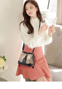 Détail d'un sac seau vintage avec imprimé beige et bandoulière en cuir noir sur modèle