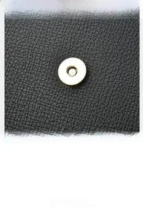 Detail of elephant grey lychee leather texture and golden magnetic metal buckle on crossbody bag