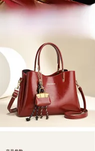 Détail d'un sac cabas en cuir verni rouge avec garniture dorée et logo de marque