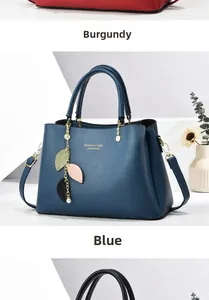 Detail of dark blue lychee leather handbag with leaf charm and gold lettering