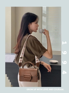 Dettaglio della borsa in pelle marrone con fibbia quadrata vintage e tracolla ricamata