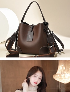 Detail view of dark brown bucket bag featuring wide fabric strap and MMF logo charm