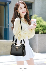 Close-up of black leather bag with golden double swan clasp and fringe detail