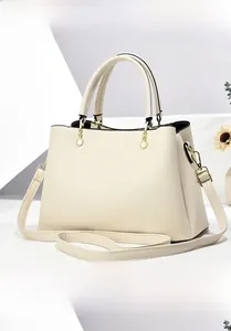 Macro view of cream-colored pebble leather texture and gold hardware on tote bag
