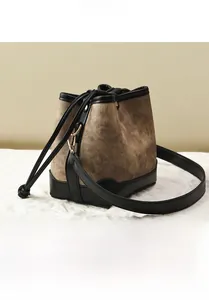 Détail du sac seau à cordon en toile marron vintage avec garniture en cuir noir et boucles dorées