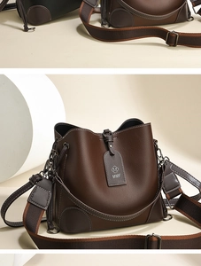 Detail of coffee brown leather bucket bag with white contrast stitching and woven strap