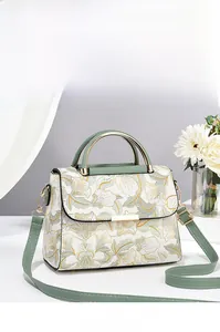 Détail du sac à main fleuri avec poignées en cuir vert et finitions en métal doré