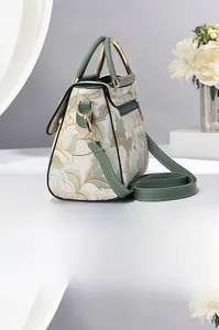 Détail de la broderie florale et de la poignée en cuir vert du sac à bandoulière