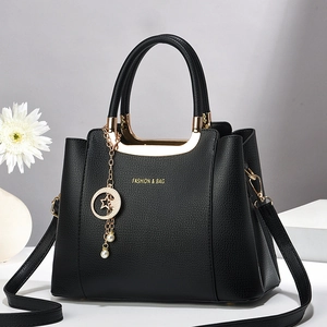 Classic black leather tote bag with gold lettering and star pearl charm on display